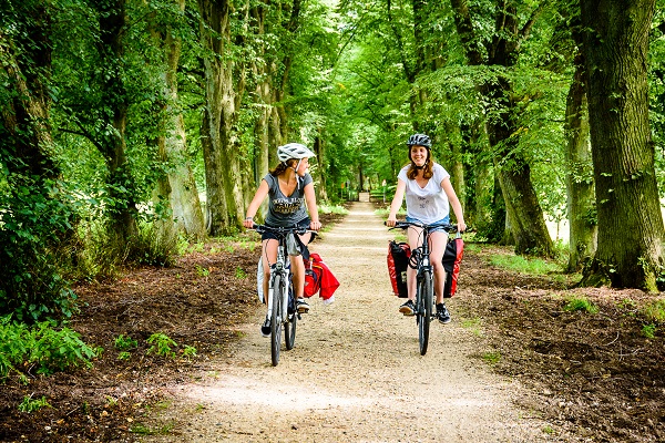 Twee vrouwen op fietsvakantie rijden over een bospad