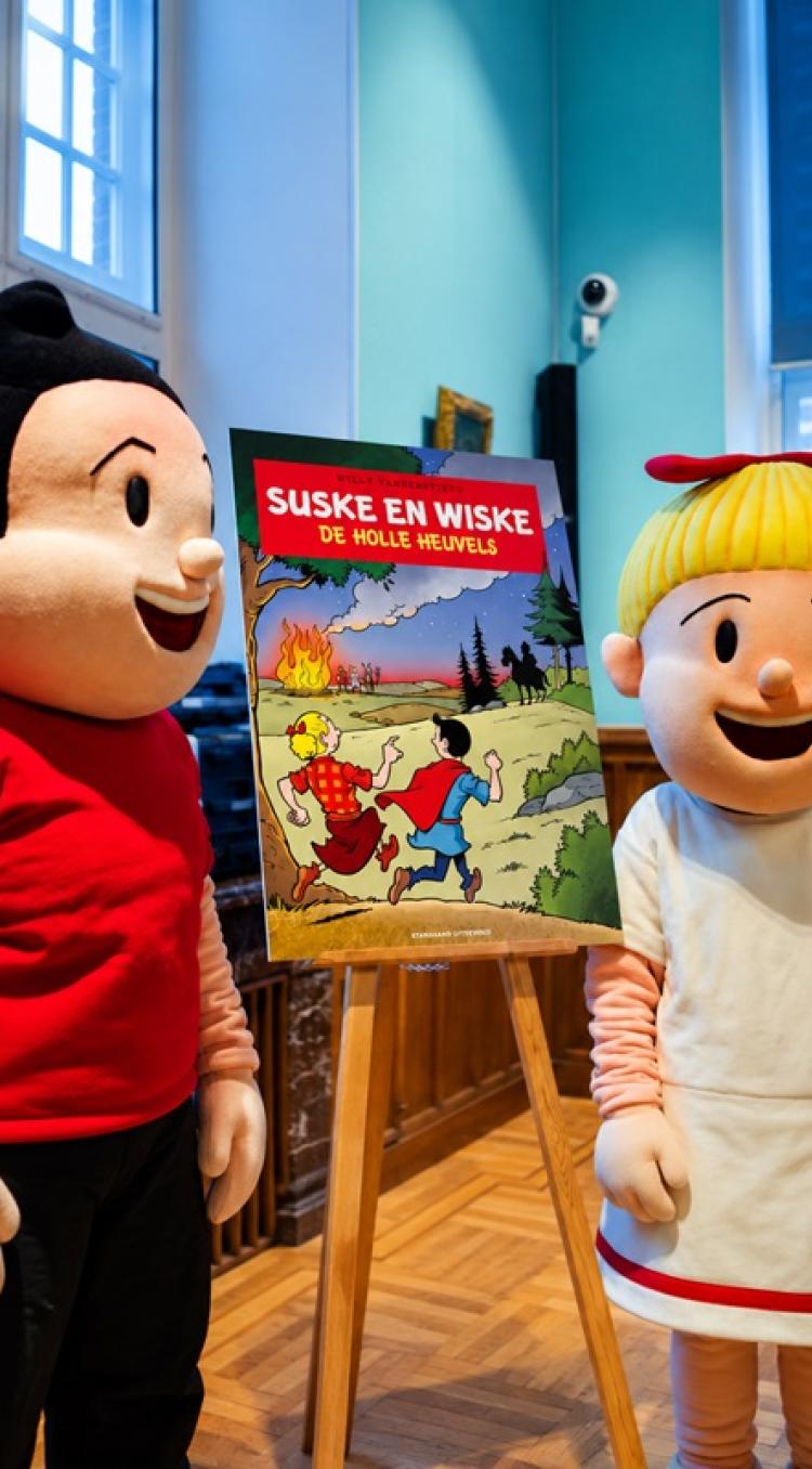 Suske en Wiske staan naast de cover van het speciale stripalbum De holle heuvels, geïnspireerd op het urnenveld op de Boshoverheide in Weert.