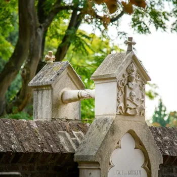 Historisch grafmonument met kruisen en versieringen tegen een groene achtergrond.